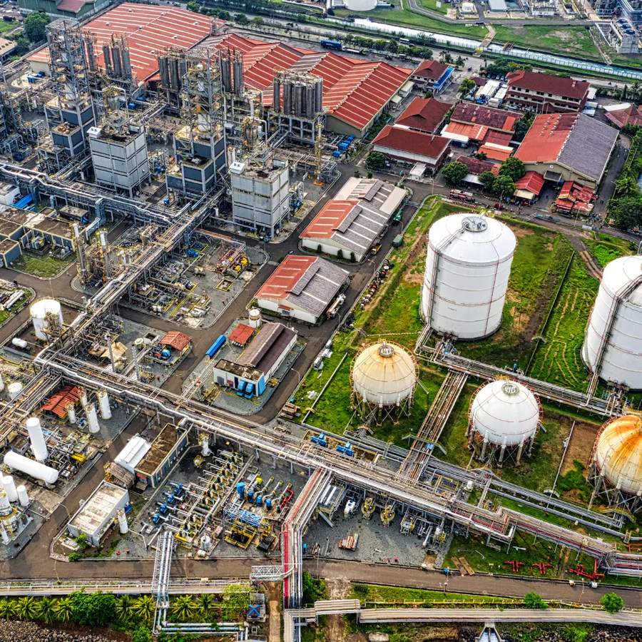 An aerial view of a chemical plant: process towers, pipe racks and rows of spherical and cylindrical storage tanks.
